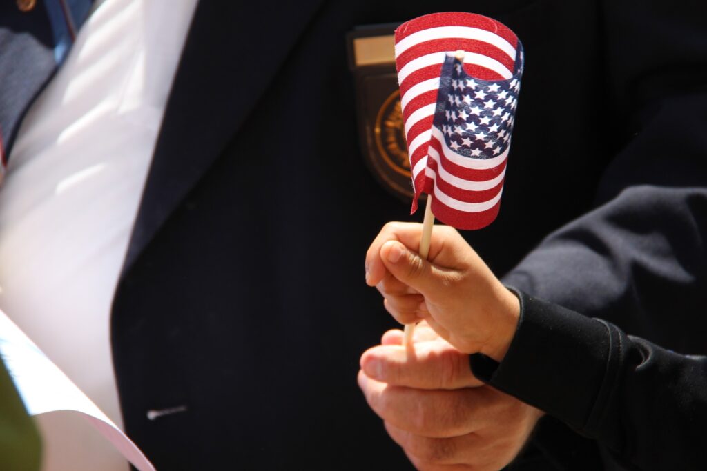 An adult hand and a child hand holding a small American flag
